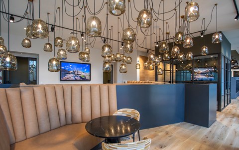 A room with a curved sofa and a TV mounted on the wall.