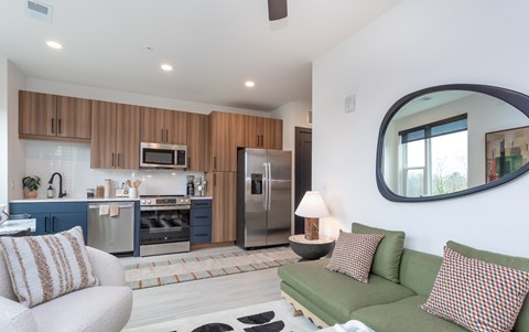 A modern kitchen with a green couch and a round mirror.