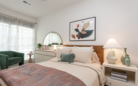 A bedroom with a large bed and a green chair.