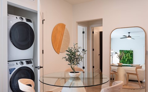 A modern kitchen with a glass table and a washing machine.