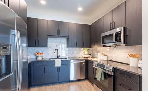 A modern kitchen with dark wood cabinets and stainless steel appliances.