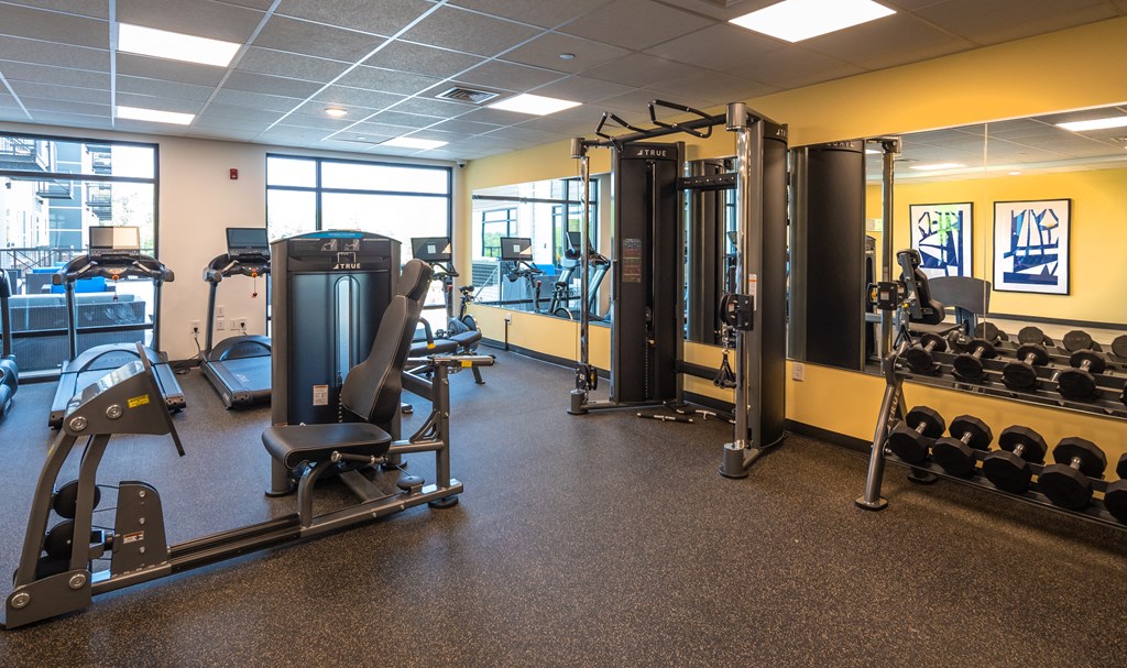 a large fitness room with cardio equipment and weights