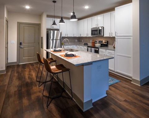 a kitchen with white cabinets and a large island with stools