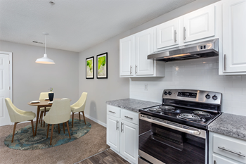 a kitchen with white cabinets and stainless steel appliances and a dining room table