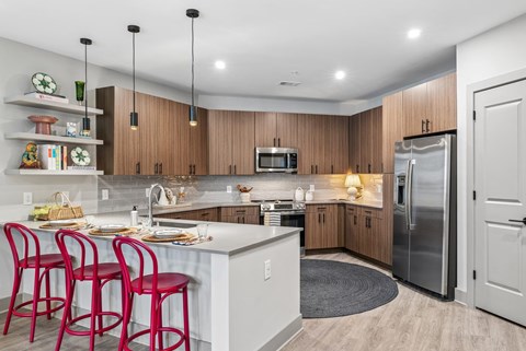 A kitchen with a white counter top and red bar stools.