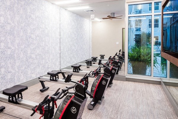 A gym with a row of exercise bikes and a window overlooking a cityscape.