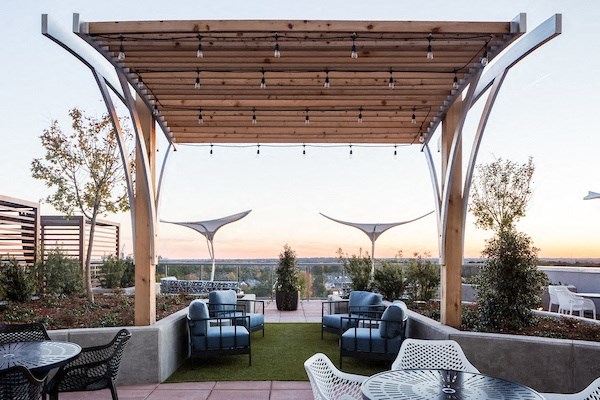 A patio with a table and chairs under a wooden pergola.