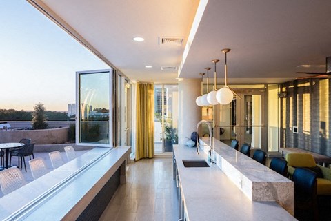 A modern kitchen with a long counter and a view of the city.