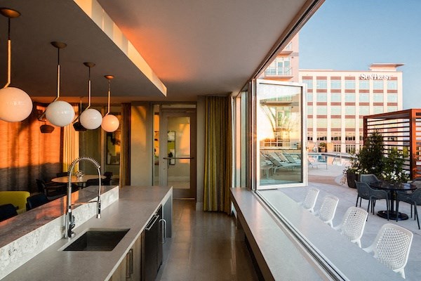 A modern kitchen with a long counter and a view of the city.