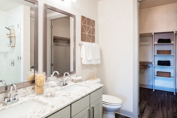 A bathroom with a toilet, sink, and mirror.