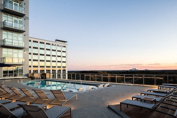 A pool area with sun loungers and a building in the background.