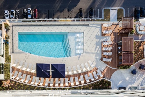 A swimming pool with a sun lounger and a white wall.