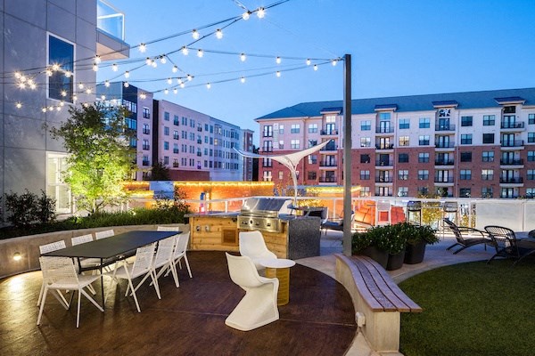 A patio with a table and chairs is lit by string lights.
