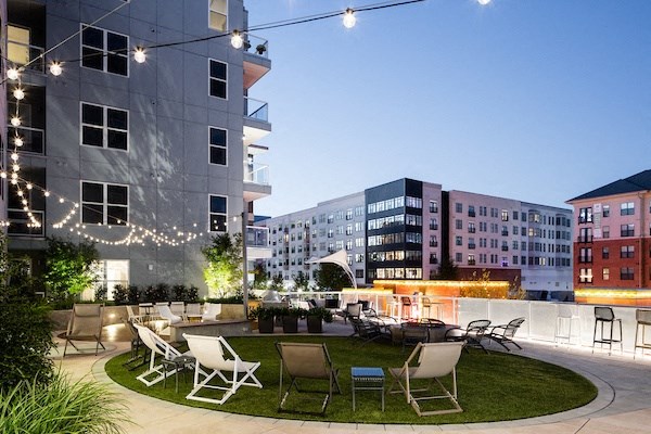 A patio with chairs and a table is surrounded by buildings.