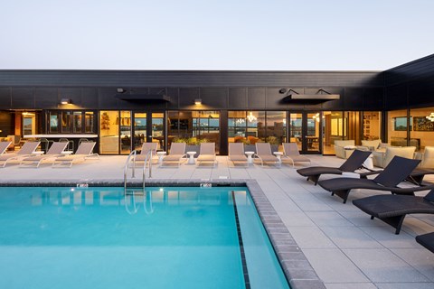 a pool with lounge chairs and a building in the background