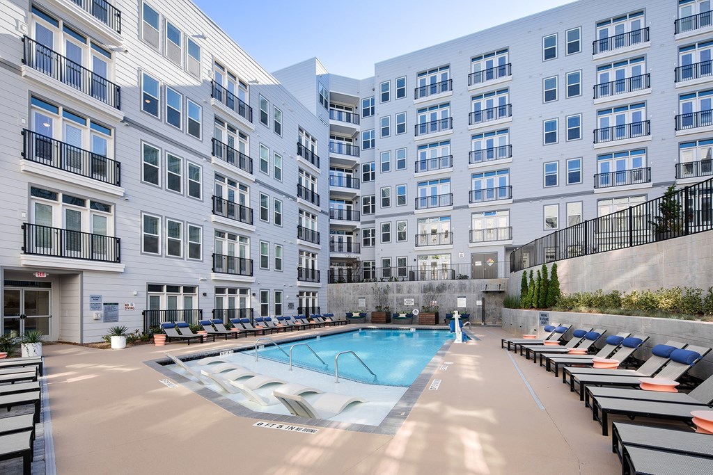 a swimming pool with lounge chairs in front of an apartment building