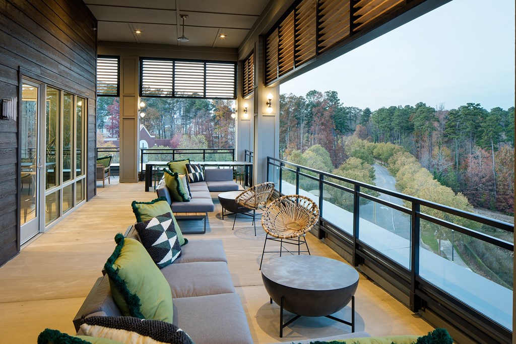 a living room with couches and chairs on a balcony overlooking a river