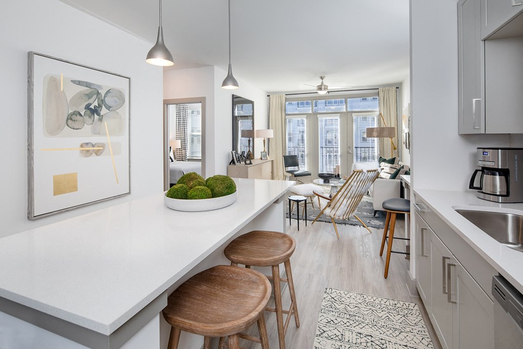 an open kitchen and living room with a white counter top and wooden stools