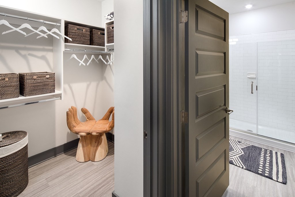 a walk in closet with a wooden chair and a white closet door