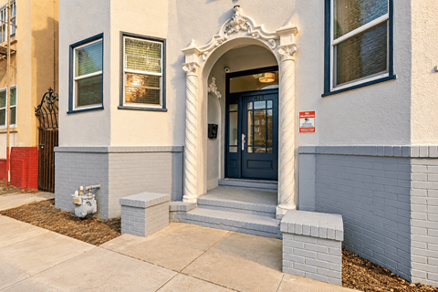 A white building with a black door and a red fire hydrant.