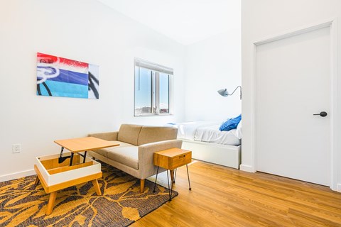 A living room with a couch, a table, and a painting on the wall.
