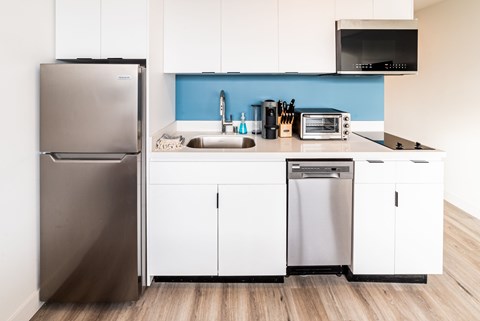 A modern kitchen with a stainless steel refrigerator and white cabinets.