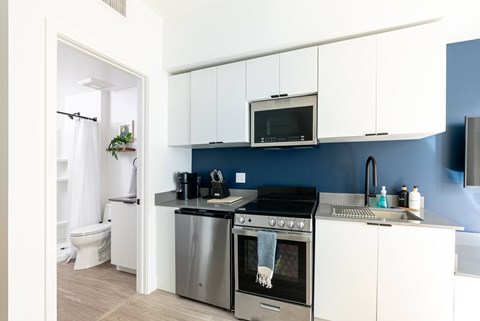 A modern kitchen with white cabinets and a blue backsplash.
