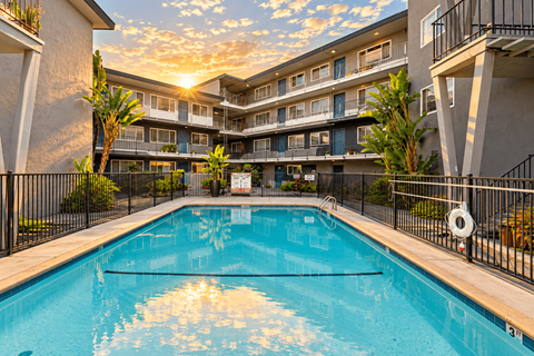 A swimming pool in front of a building with sunlight shining through the clouds.