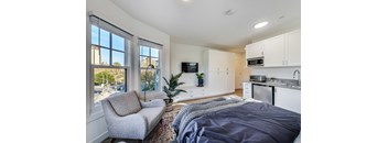 A bedroom with a bed, chair, and a window overlooking a parking lot.