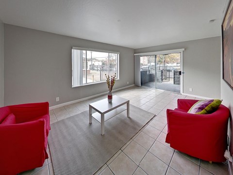 A living room with red chairs and a glass table.
