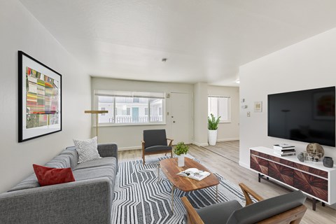 A living room with a grey couch, a wooden coffee table, and a television on a cabinet.