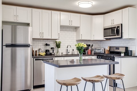 A kitchen with white cabinets and a stainless steel refrigerator.