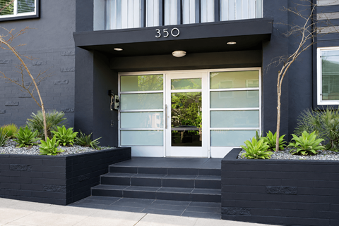 A modern house entrance with a glass door and steps leading up to it.