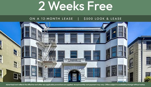 A large white and black building with a sign offering 2 weeks free on a 12-month lease.