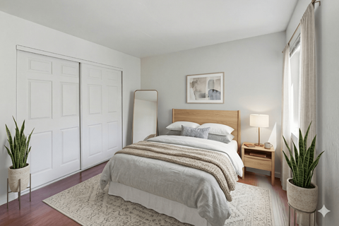 A bedroom with a large bed and a potted plant.