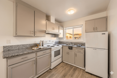A kitchen with white appliances and wooden floors.