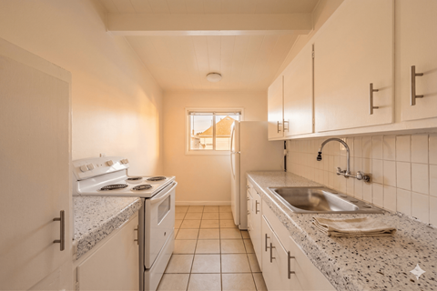 A kitchen with white cabinets and a granite countertop.