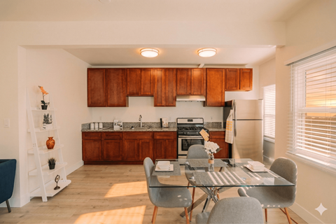 A kitchen with wooden cabinets and a glass table with chairs.