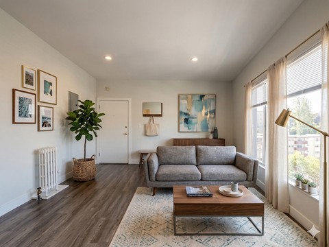 A living room with a grey couch, a wooden coffee table, and a painting on the wall.