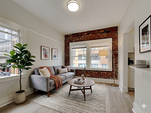A living room with a grey couch and a brown coffee table.