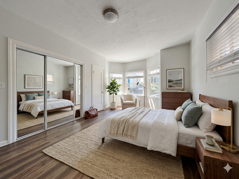 A bedroom with a large bed and a mirror on the wall.