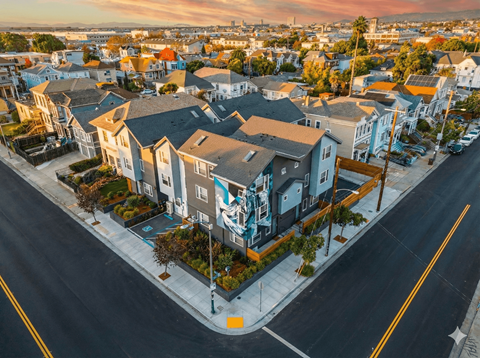 A street view of a residential area with houses and parked cars.
