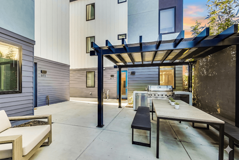 A patio with a table and chairs under a pergola.