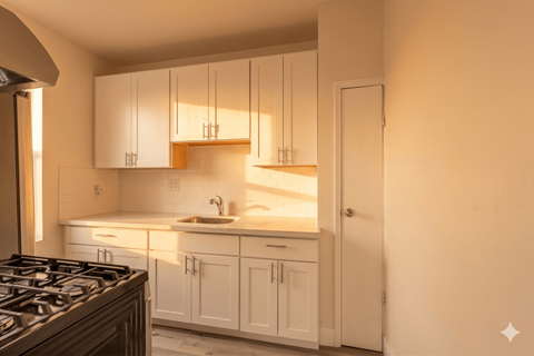 A kitchen with white cabinets and a stove top oven.