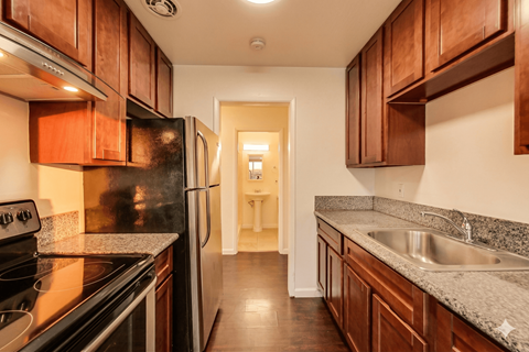 A kitchen with wooden cabinets and a black refrigerator.