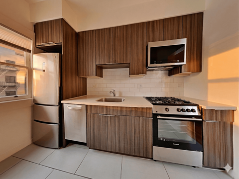 A modern kitchen with a stove, sink, and refrigerator.
