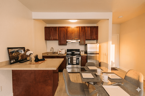A kitchen with brown cabinets and a dining table set for two.