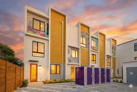 A modern apartment building with a purple storage unit in front.
