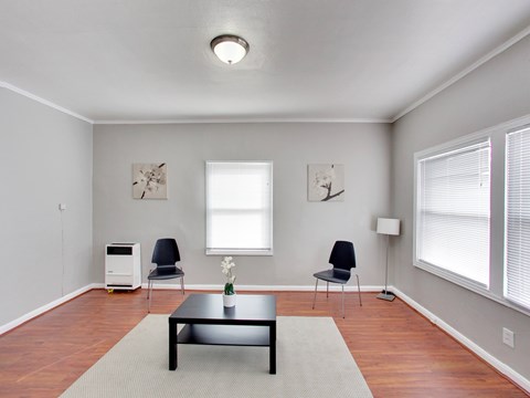A living room with a black coffee table and two chairs.