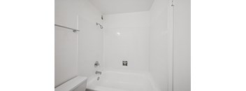 A white bathroom with a tub and toilet.